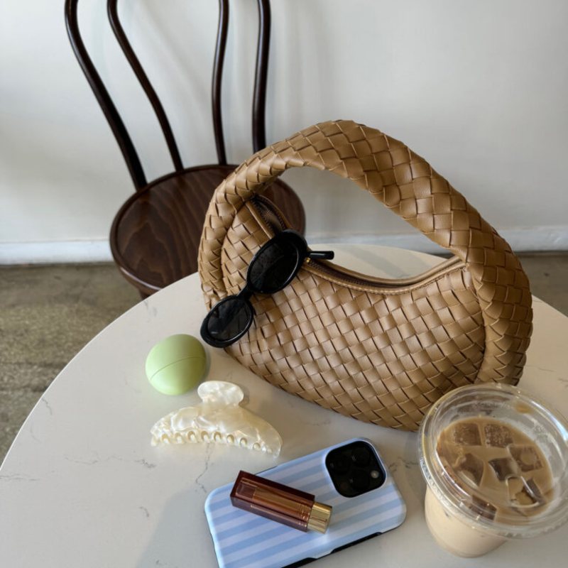 Woven bag, sunglasses and iced coffee on a cafe table
